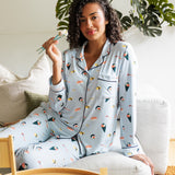 Woman wearing a sushi-themed blue pajama set sitting on a couch with a small bamboo basket of sushi.
---1605 1