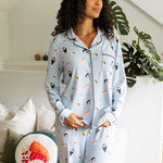 Woman wearing a light blue pajama set with colorful sushi patterns in a cozy living room.
---PJ 2