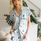 Woman wearing a sushi-themed pajama set in a home setting with plants.
---PJ 2