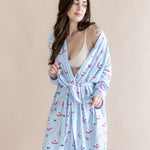 Woman wearing a light blue robe with a pattern of pink mahjong on a beige background