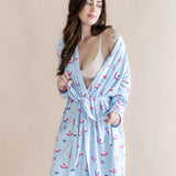 Woman wearing a light blue robe with a pattern of pink mahjong on a beige background