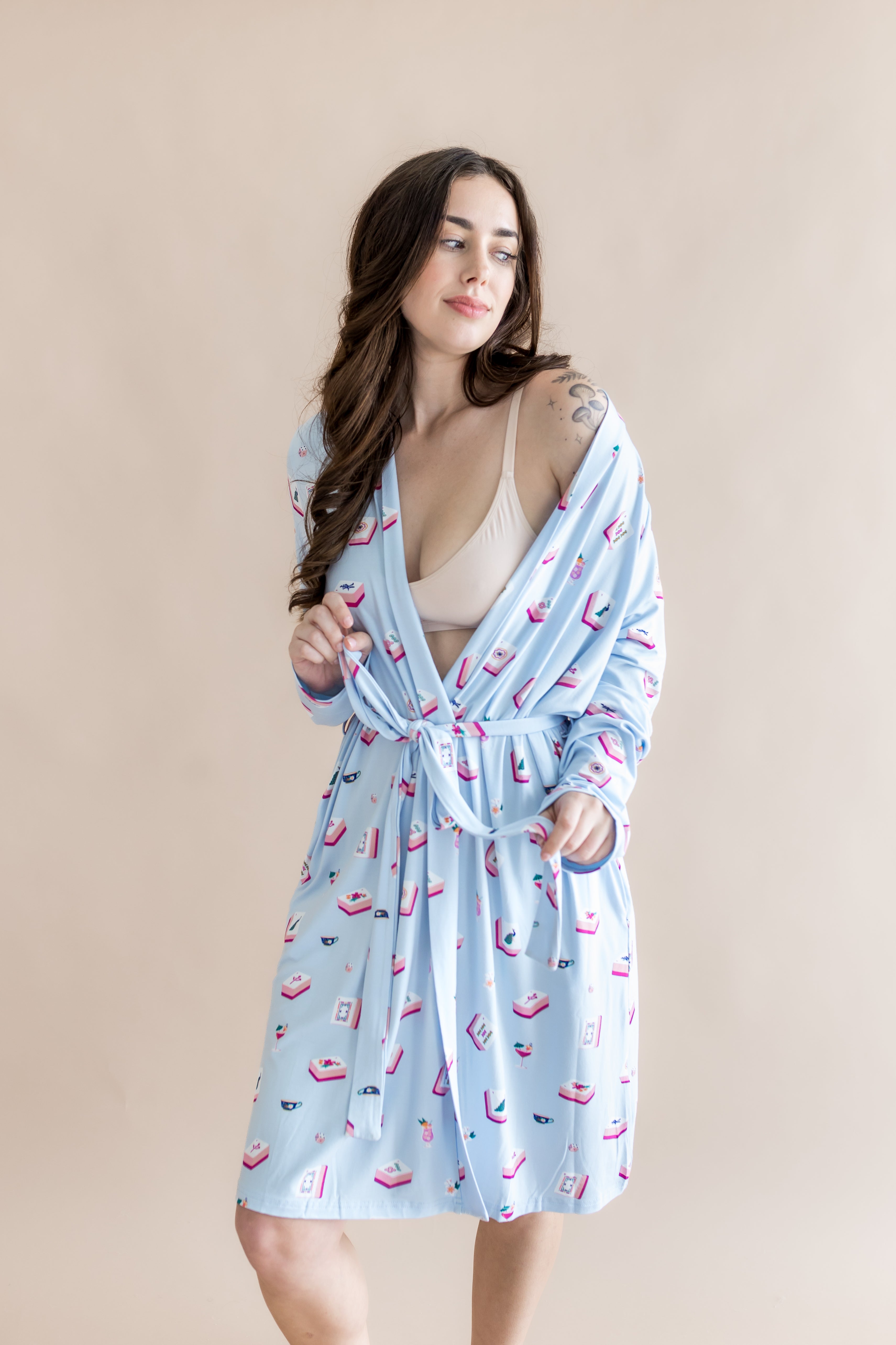 Woman wearing a light blue robe with a pattern of pink mahjong on a beige background