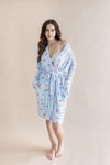 Woman wearing a light blue robe with pink mahjong tiles pattern on a beige background ::: Model is 5'7" wearing size XS/S ///