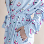 Light blue robe with colorful pattern worn by a person on a beige background