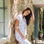 Woman wearing a light blue pajama set with mahjong pattern sitting on a stone wall.