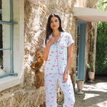 Woman wearing a patterned pajama set standing in front of a stone building.