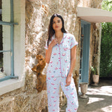 Woman wearing a patterned pajama set standing in front of a stone building.