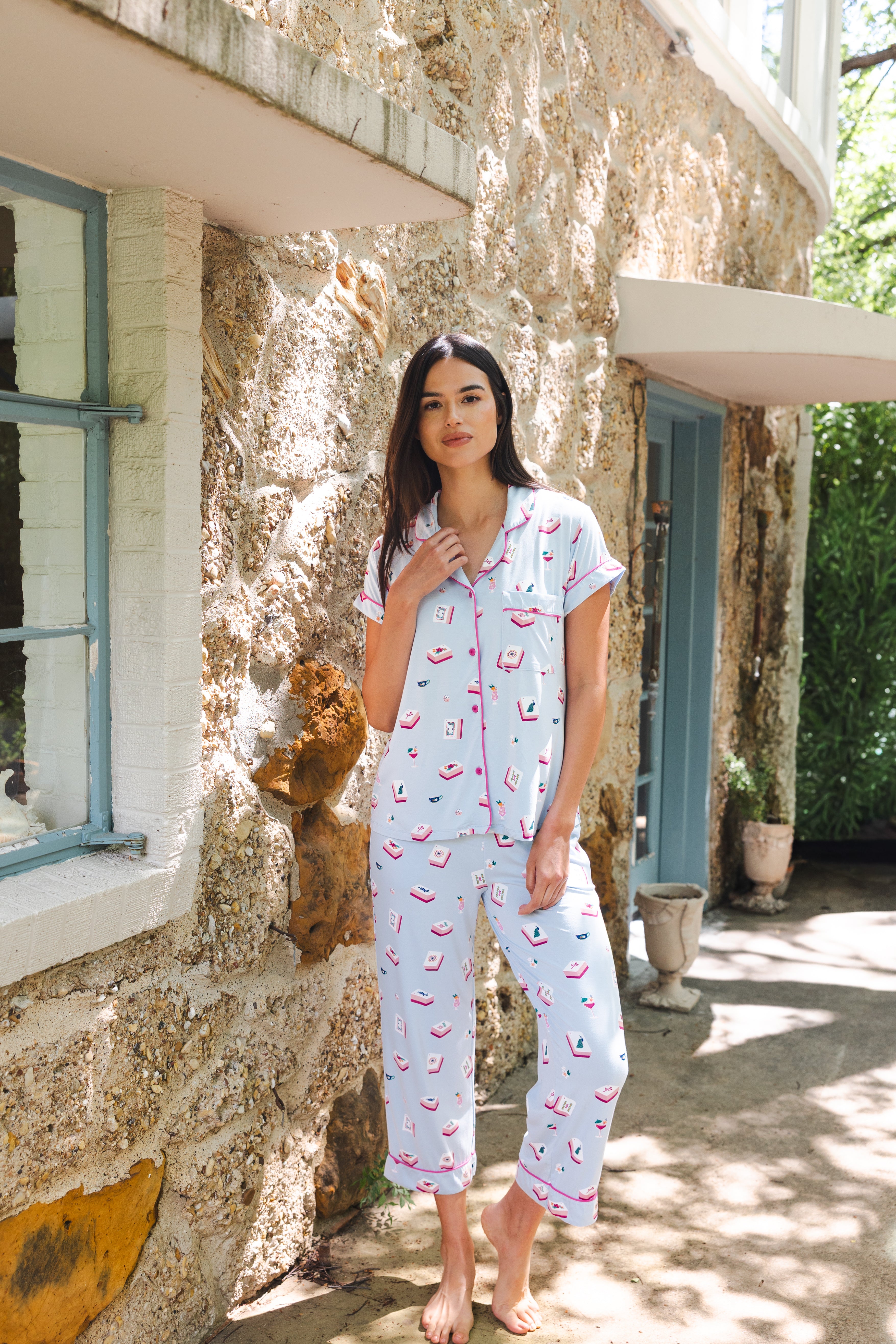 Woman wearing a patterned pajama set standing in front of a stone building.