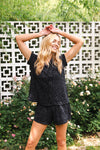 Woman in black leopard short pj set standing outdoors with greenery and a decorative wall in the background ::: Model is 5'9" wearing size XS ///