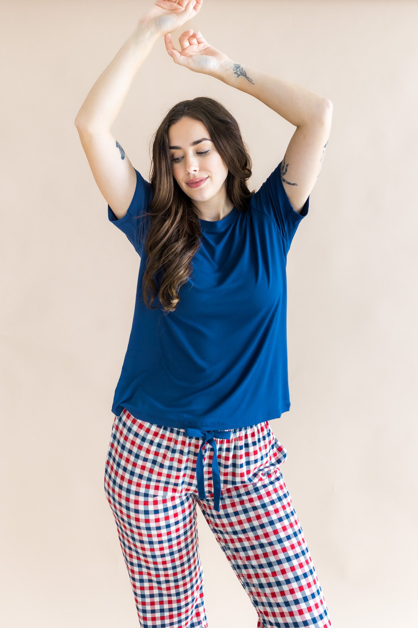 Model with arms over her head while  wearing the Women's Lounge Pants in Patriotic Gingham paired with a crew neck in Tahoe