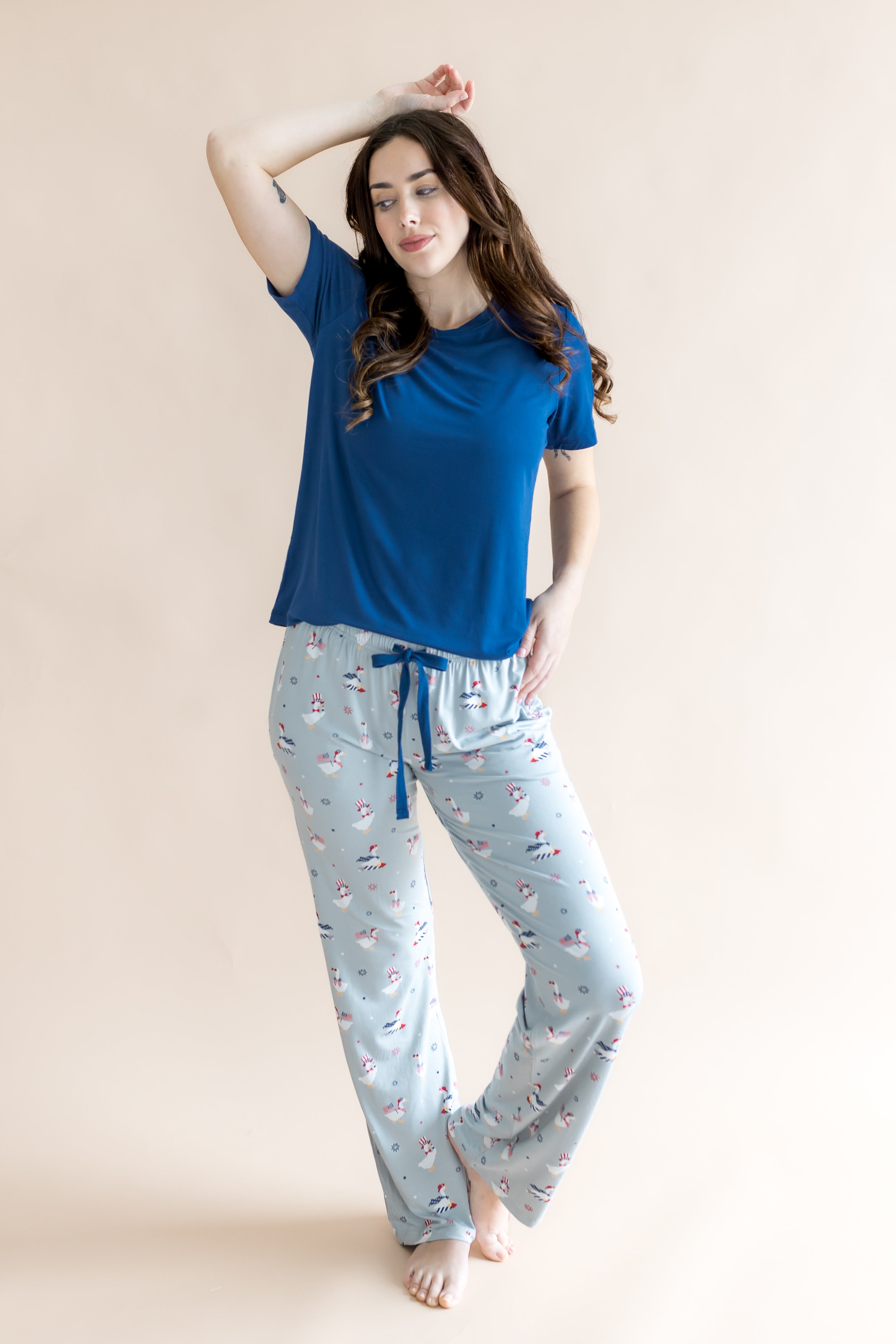 Model looking to the side with arm on her head and one knee bent while wearing the Women's Lounge Pants in Patriotic Goose paired with a crew neck in Tahoe 