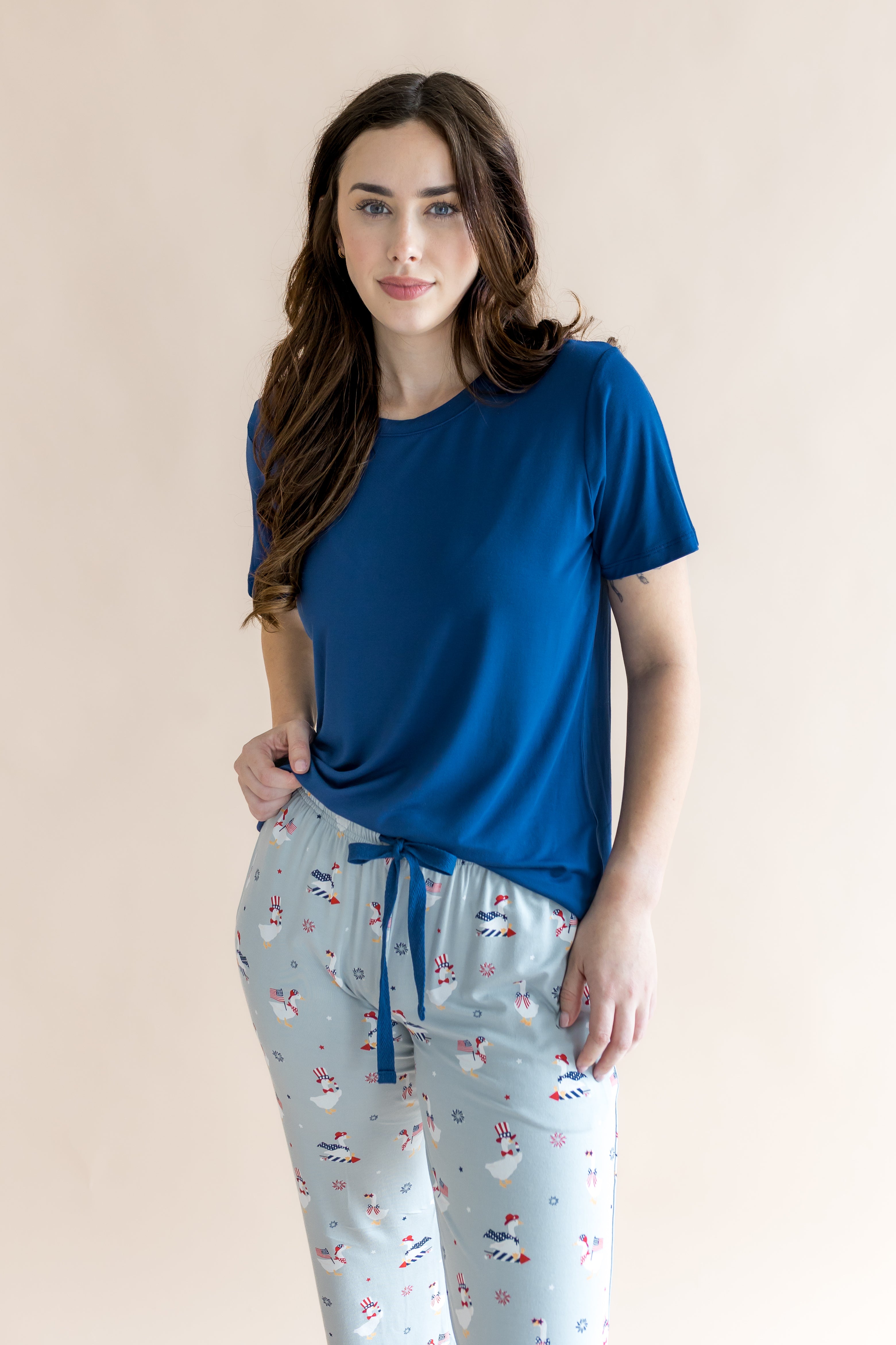 Brunette model wearing the Women's Lounge Pants in Patriotic Goose paired with a crew neck in Tahoe in front of a beige background 