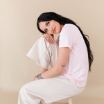woman sitting on a stool modeling Women's Crew Neck Tee in Sakura 