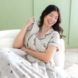Laughing woman wrapped in the Throw Blanket in Starry Icon 1.0 while wearing the matching Short Sleeve Pajama Set 