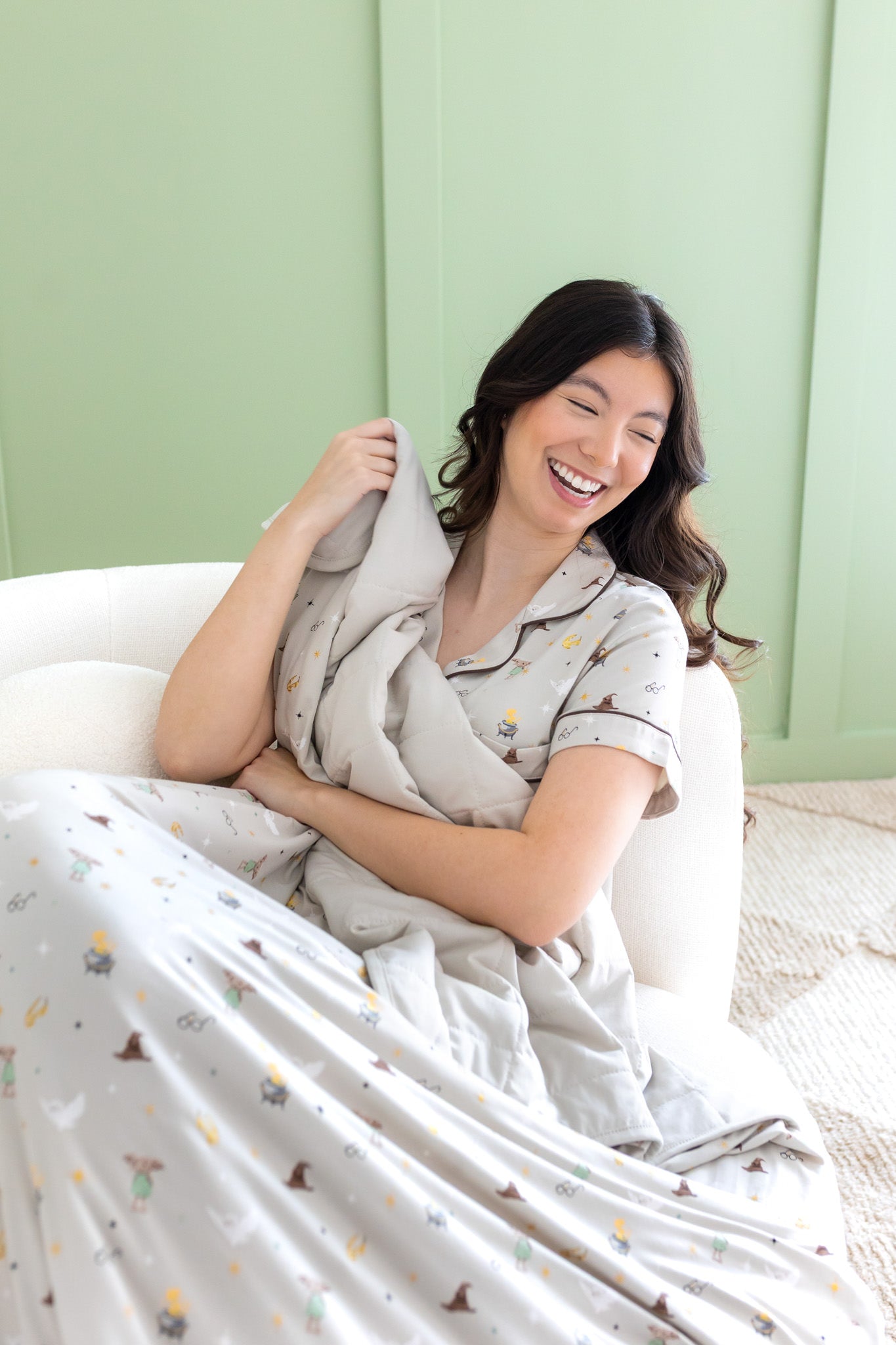 Laughing woman wrapped in the Throw Blanket in Starry Icon 1.0 while wearing the matching Short Sleeve Pajama Set 