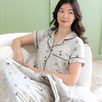 Woman looking to the side in Short Sleeve Pajama Set with the matching Throw Blanket in Starry Icon 1.0  laying on her lap 