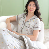 Woman looking to the side in Short Sleeve Pajama Set with the matching Throw Blanket in Starry Icon 1.0  laying on her lap 