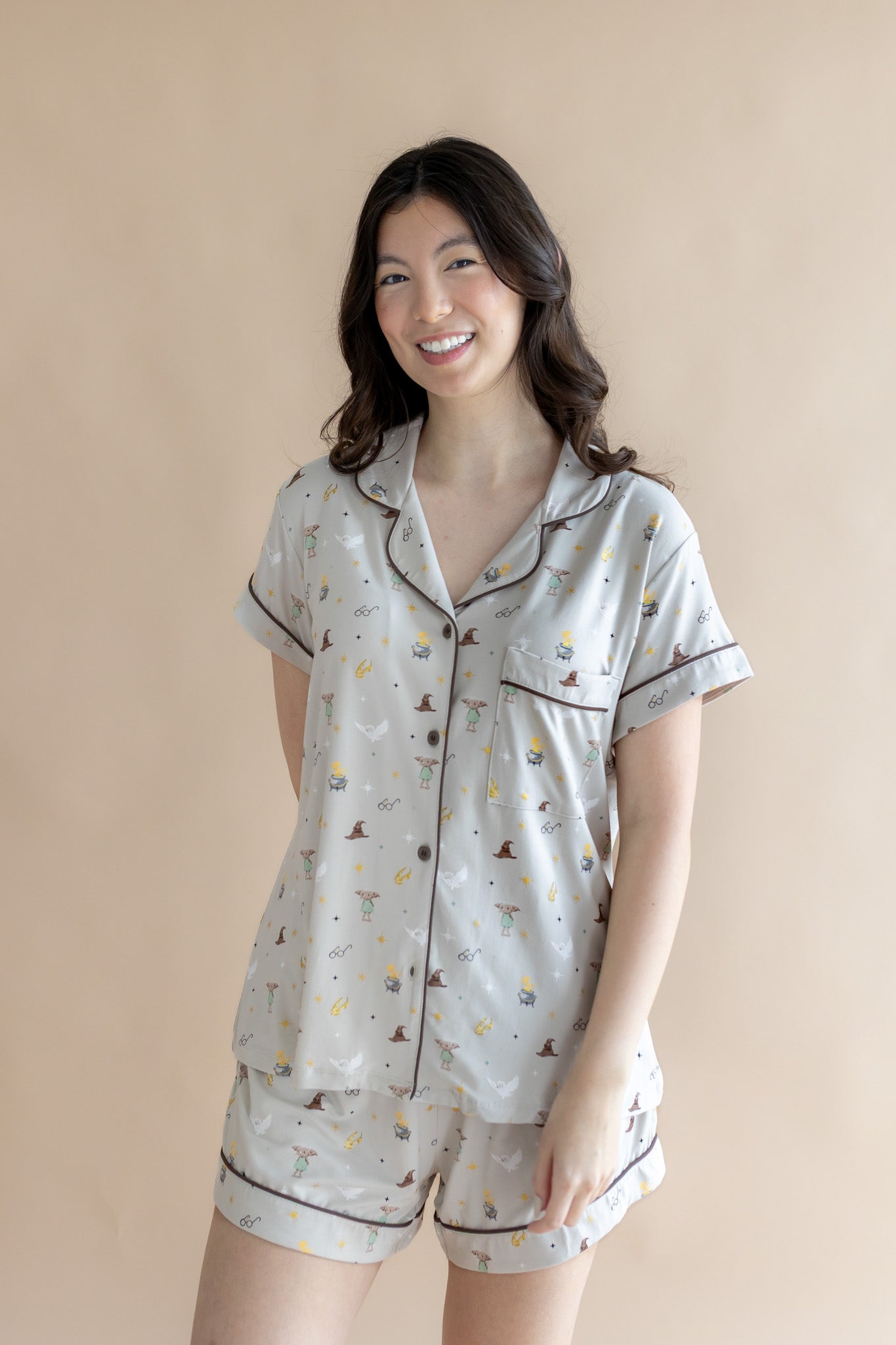 Smiling model standing infront of a beige back ground while wearing the Short Sleeve Pajama Set in Starry Icon 