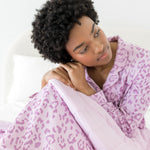 Model under an Adult Blanket in Thistle Leopard print wearing similar print long sleeve pajama on a white background