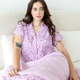 Model posing under Thistle Leopard print Throw Blanket wearing a similar print shirt on a white background