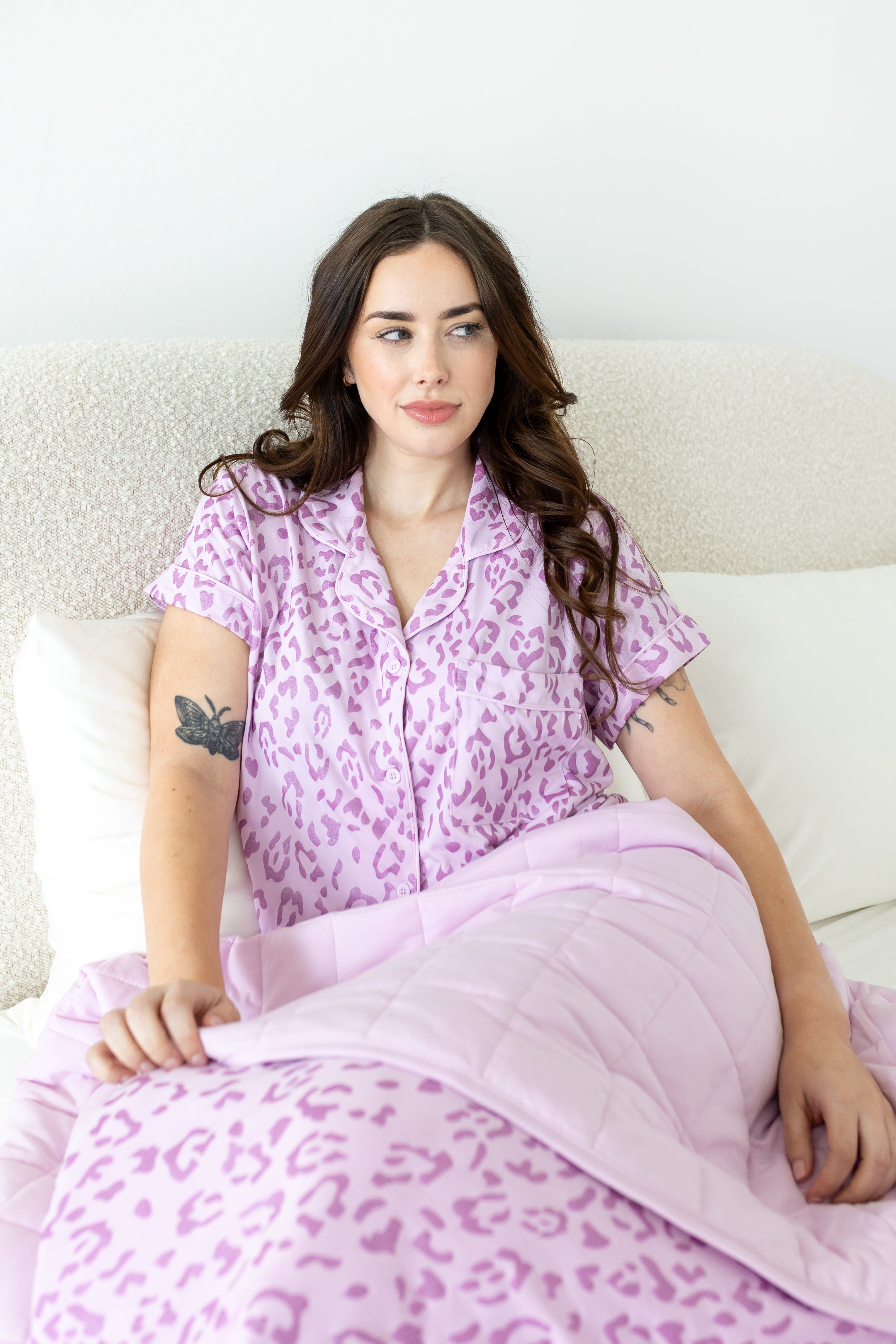Model posing under Thistle Leopard print Throw Blanket wearing a similar print shirt on a white background