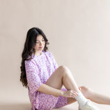 Model sitting in Women’s Biker Short Set in Thistle Leopard print with white socks and shoes on a beige background