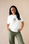 Female posing wearing the Women's Graphic Tee in The Child™ paired with dark green pants

::: Model is 5'6" wearing size M ///