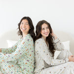 Models sitting back to back while wearing the Long Sleeve Pajama Set in Honeydukes and Starry Icon 