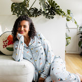 Woman sitting in a living room wearing a light blue pajama set with colorful sushi patterns