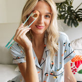 Woman holding a sushi in chopsticks wearing blue Short sleeve women's pajamas set in sushi print sitting on a white couch