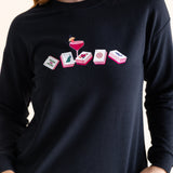 Person wearing a black long-sleeve sweatshirt with a mahjong graphic design on a plain background