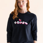 Woman wearing a black sweatshirt with colorful mahjong design on a beige background