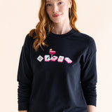 Woman wearing a black sweatshirt with colorful mahjong design on a beige background