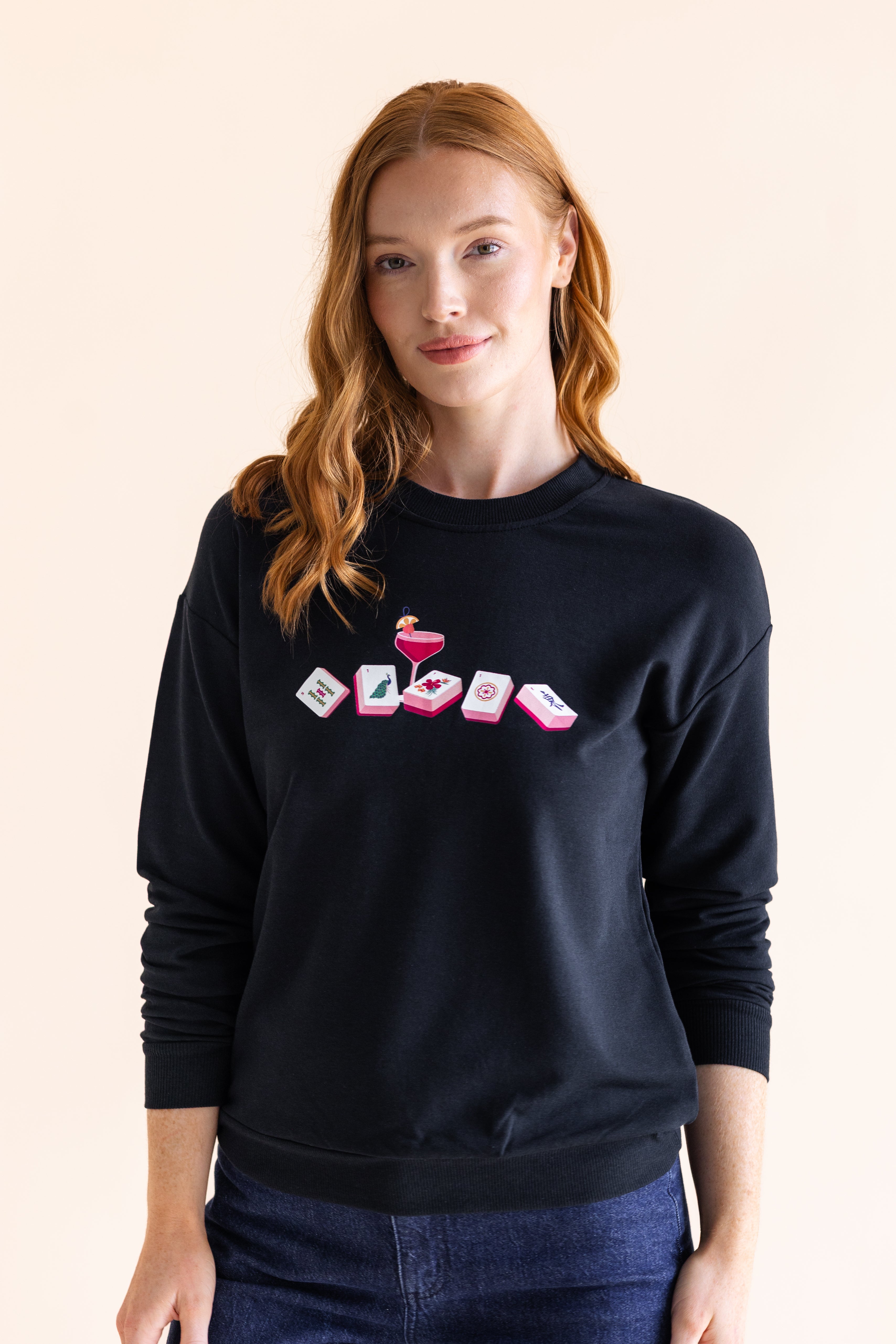 Woman wearing a black sweatshirt with colorful mahjong design on a beige background