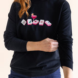 Person wearing a black sweatshirt with a mahjong design on a plain background