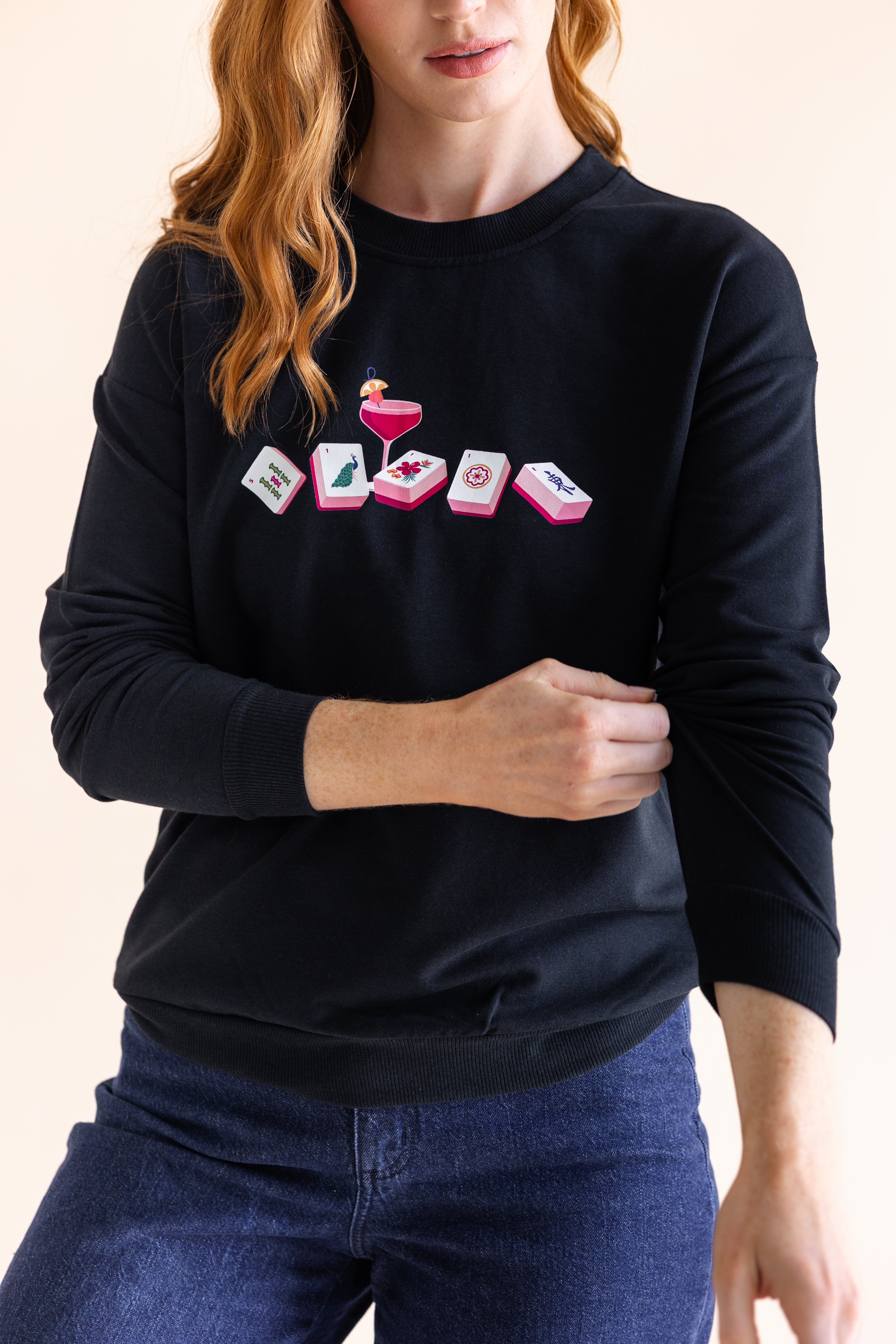 Person wearing a black sweatshirt with a mahjong design on a plain background