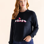 Woman wearing a black sweatshirt with colorful mahjong symbols on a beige background ::: Model is 5'8" wearing size S ///
