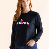 Woman wearing a black sweatshirt with colorful mahjong symbols on a beige background ::: Model is 5'8" wearing size S ///
