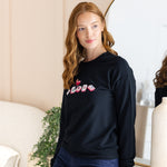 Woman wearing a black sweatshirt with colorful mahjong design in a room.