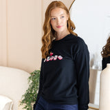 Woman wearing a black sweatshirt with colorful mahjong design in a room.