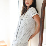 Woman wearing a polka dot pajama set standing in a softly lit room.