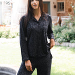 Woman wearing a black leopard patterned outfit standing outdoors in a garden. ::: Model is 5'10" wearing size S ///