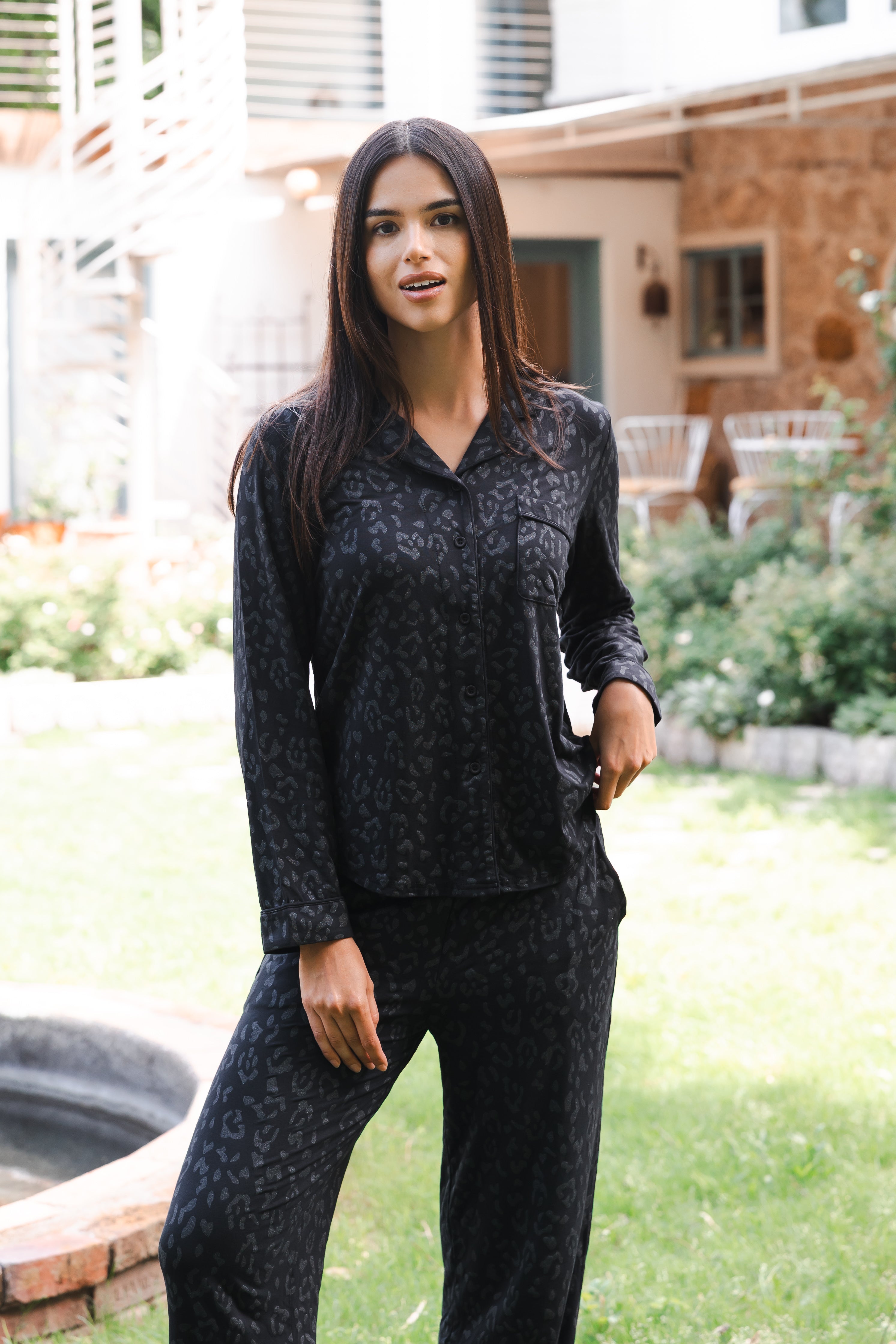 Woman wearing a black leopard patterned outfit standing outdoors in a garden. 