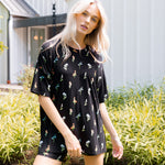 Model wearing Women’s Biker Short Set in Midnight Wildflower print outdoors in sunlight with bushes in the background