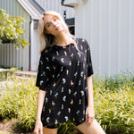Model standing in front of a house with white siding while wearing the Kyte Women’s Biker Short Set in Midnight Wildflower