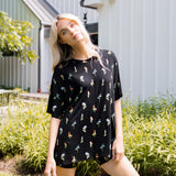 Model standing in front of a house with white siding while wearing the Kyte Women’s Biker Short Set in Midnight Wildflower