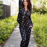 Model posing outdoors surrounded by trees in Long-Sleeved Women's Pajama Set in Midnight Wildflower 
print ---1605 3