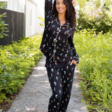 Model posing outdoors surrounded by trees in Long-Sleeved Women's Pajama Set in Midnight Wildflower 
print ---1605 3