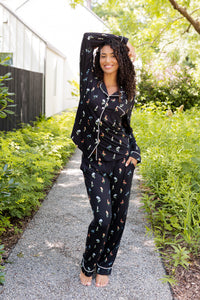 Model posing outdoors surrounded by trees in Long-Sleeved Women's Pajama Set in Midnight Wildflower 
print ---1605 3