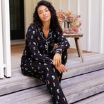 Model wearing Long-Sleeved Women's Pajama Set in Midnight Wildflower print sitting on outdoor steps ---PJ 4